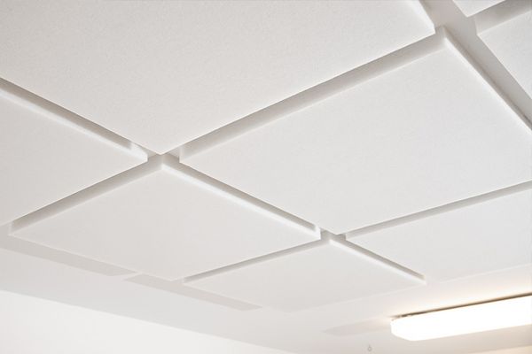 weiße, quadratische Schallabsorber aus Vlies. Montiert mit Schattenfuge an der Decke.